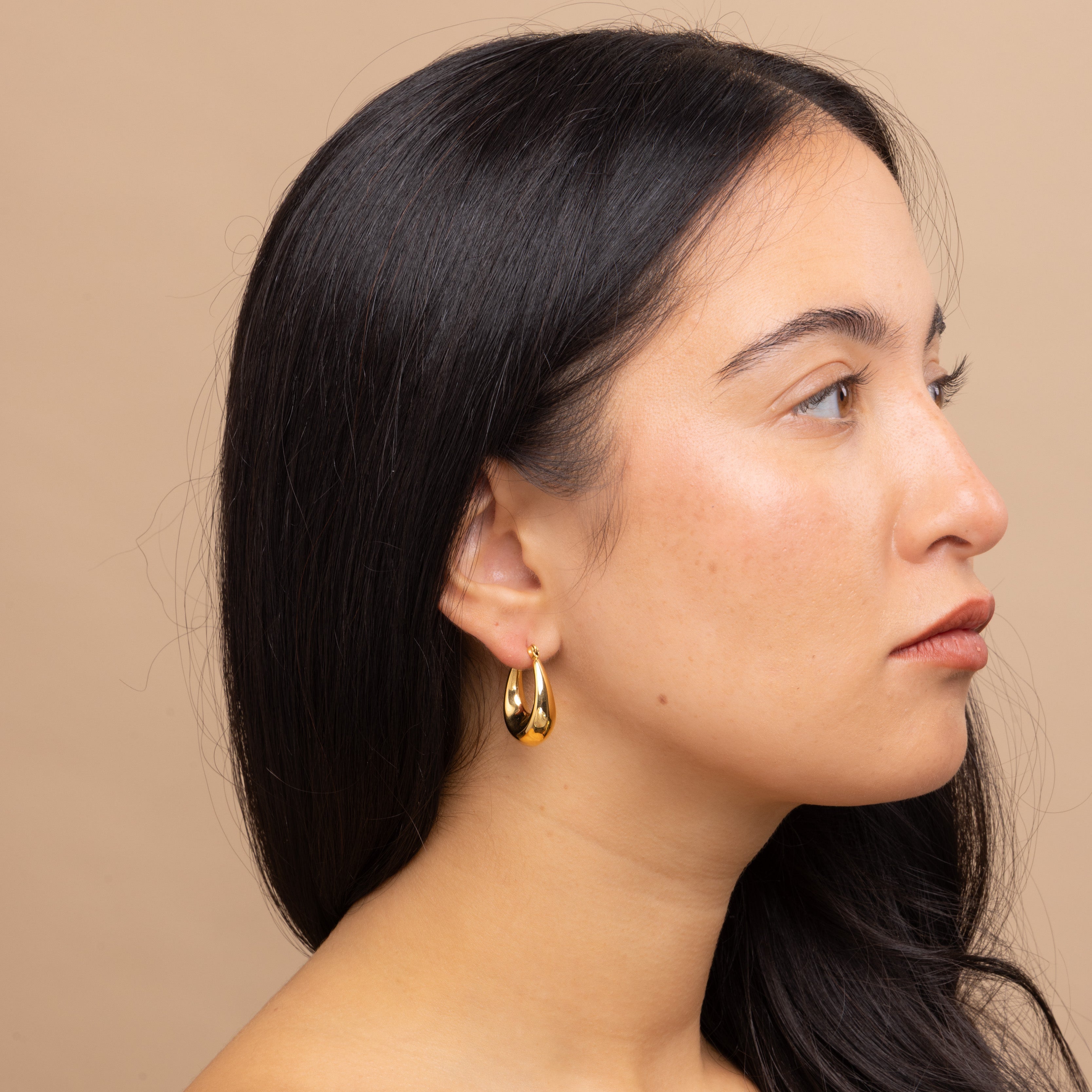 Model showcasing Gold Thick Oval Hoop Earrings by Zoi Era β bestselling waterproof and tarnish-free oval hoops in a modern chunky design.