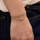 gold tennis bracelet paired with dainty heart bracelet