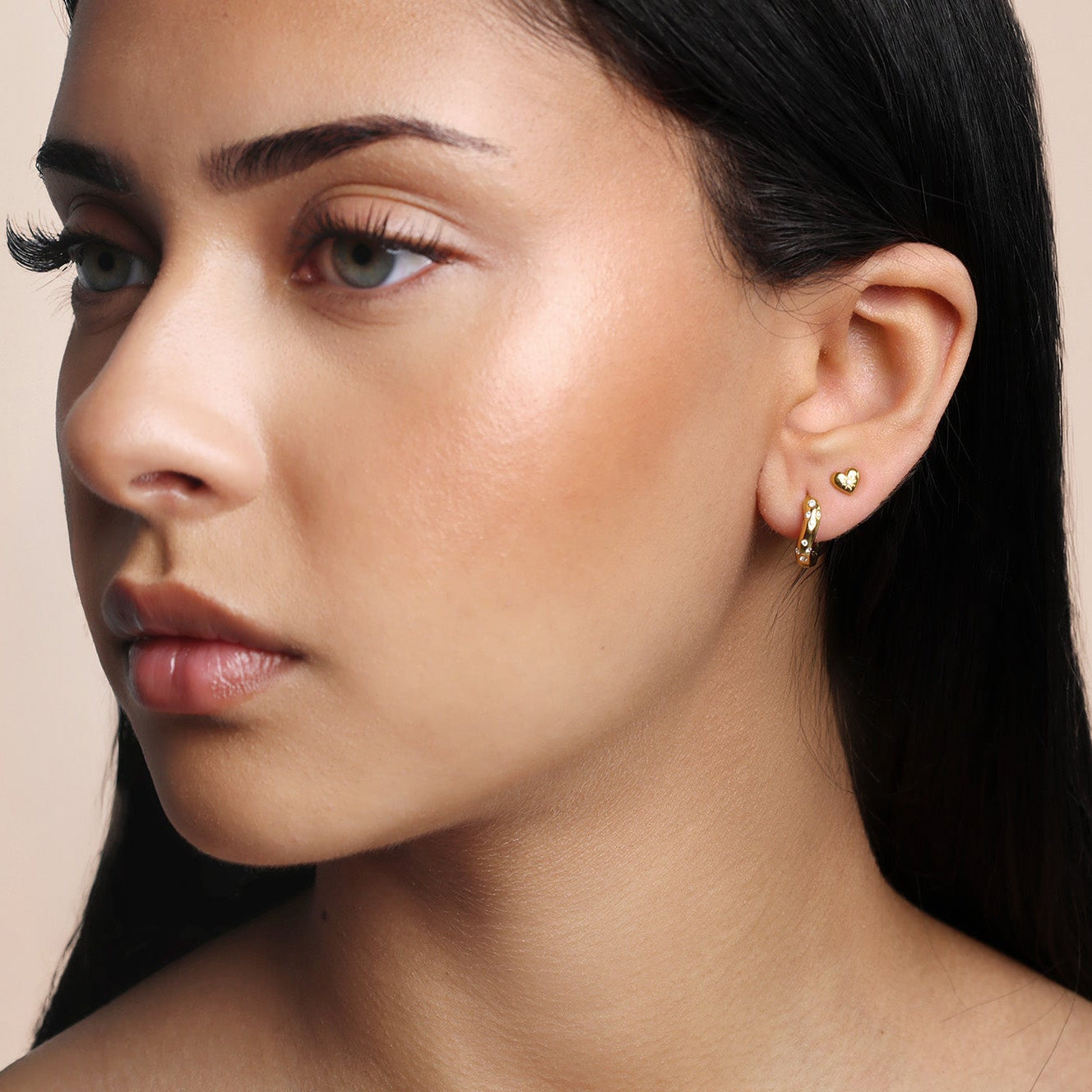 Close-up of a woman wearing anti-tarnish  gold earrings stack with a neutral background