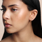 Close-up of a woman wearing anti-tarnish  gold earrings stack with a neutral background